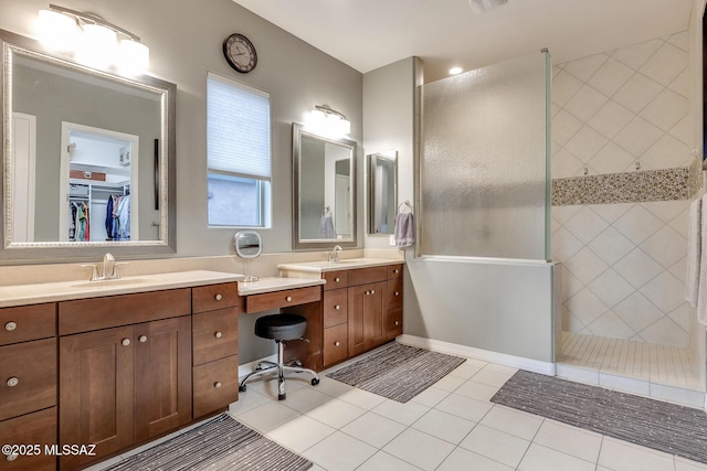 full bathroom featuring a walk in shower, two vanities, a sink, and tile patterned floors