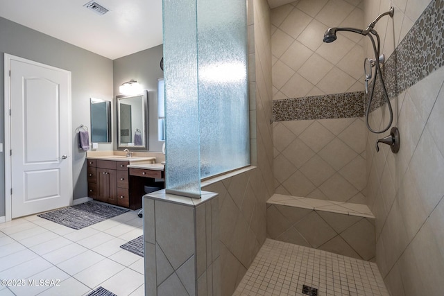 full bath featuring tile patterned flooring, visible vents, vanity, and tiled shower