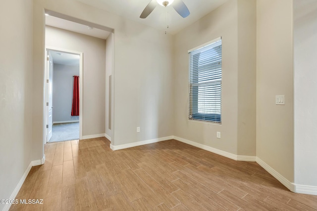 spare room featuring ceiling fan, light wood-type flooring, and baseboards