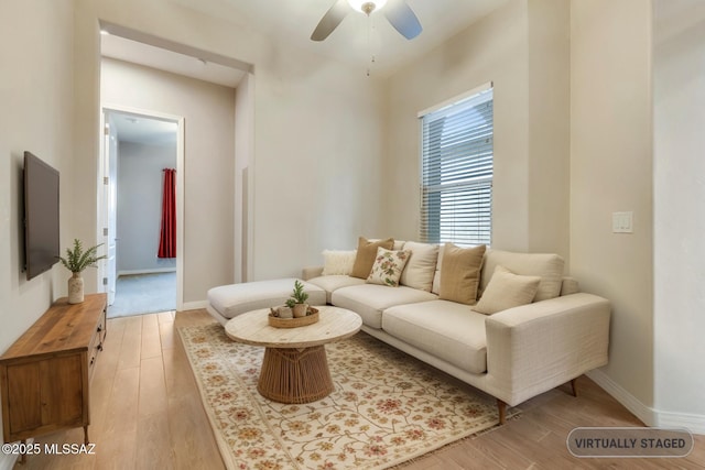 living area with a ceiling fan, light wood-type flooring, and baseboards