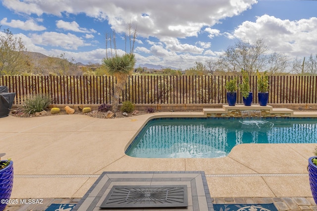 view of pool featuring a patio area, fence, a mountain view, and a fenced in pool