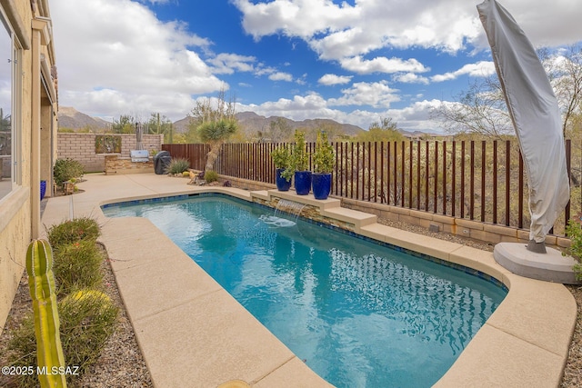 view of swimming pool with a fenced backyard, a mountain view, a fenced in pool, and a patio