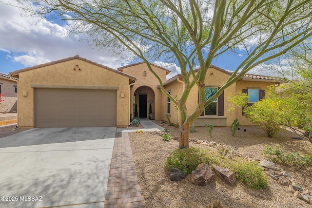 mediterranean / spanish-style house featuring an attached garage, a tiled roof, concrete driveway, and stucco siding