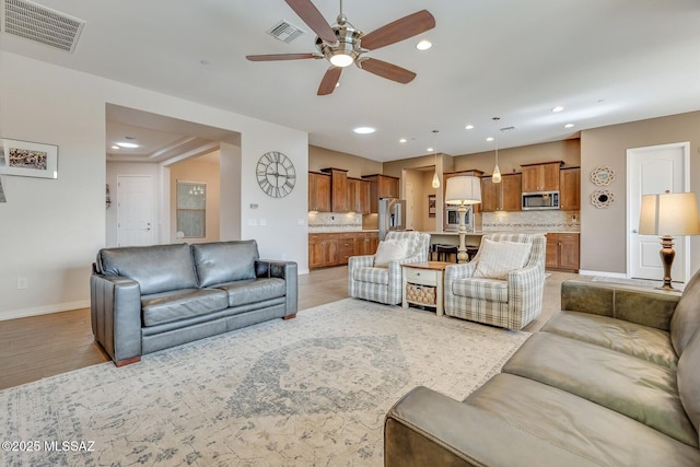 living area featuring recessed lighting, visible vents, light wood-style flooring, and baseboards