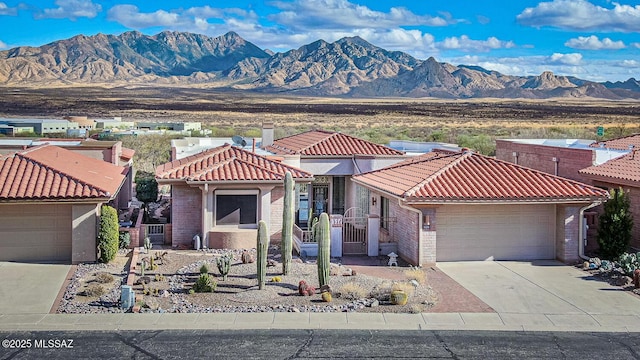 view of front of property with concrete driveway, a tile roof, a mountain view, and brick siding