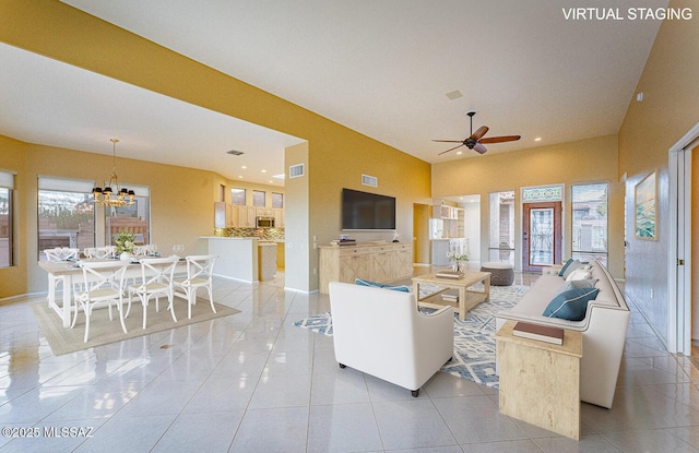 living room featuring a healthy amount of sunlight, light tile patterned flooring, visible vents, and ceiling fan with notable chandelier