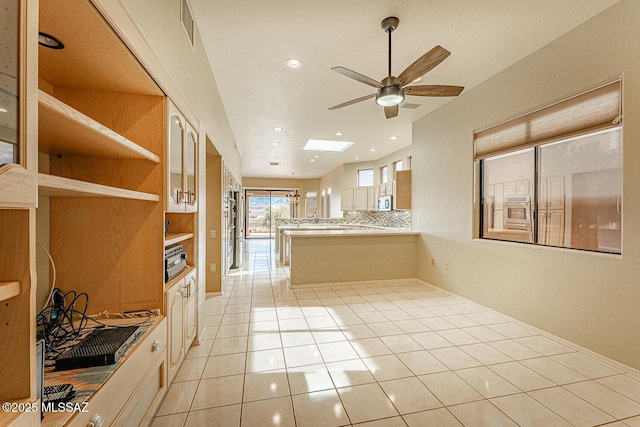 kitchen featuring a skylight, light tile patterned floors, visible vents, light countertops, and a peninsula