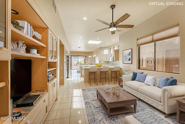 living room with light tile patterned floors, a skylight, visible vents, a ceiling fan, and recessed lighting