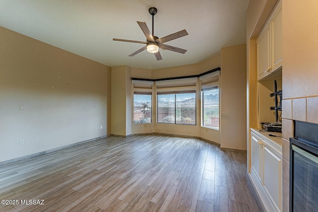 unfurnished living room with ceiling fan and light wood finished floors