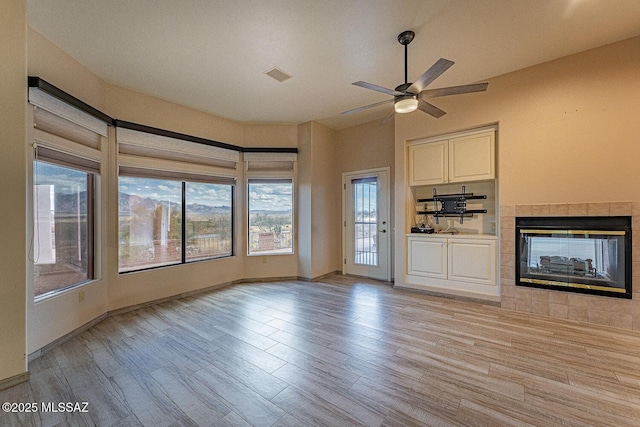 unfurnished living room with ceiling fan, light wood-style flooring, a fireplace, and visible vents