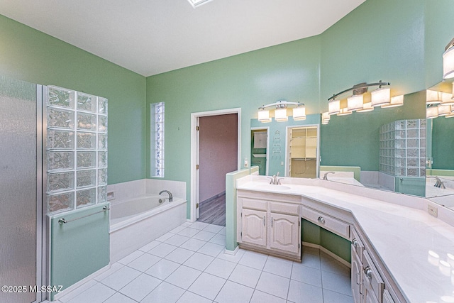 bathroom featuring a garden tub, vanity, vaulted ceiling, a spacious closet, and tile patterned floors