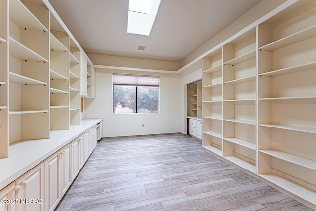 unfurnished office featuring light wood-type flooring and a skylight