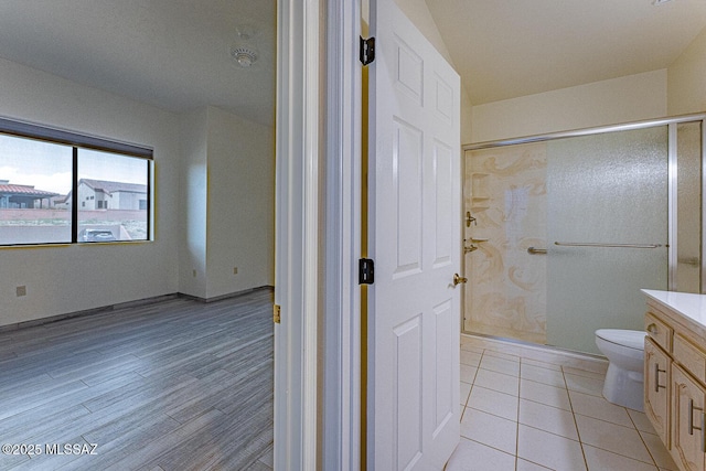 full bath featuring toilet, wood finished floors, walk in shower, and vanity