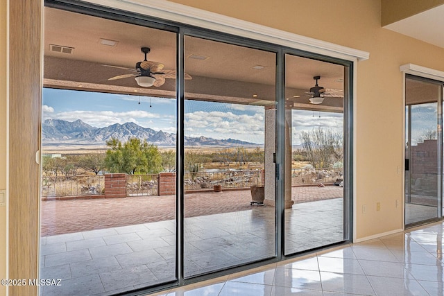 doorway to outside featuring light tile patterned floors, a mountain view, visible vents, baseboards, and a ceiling fan