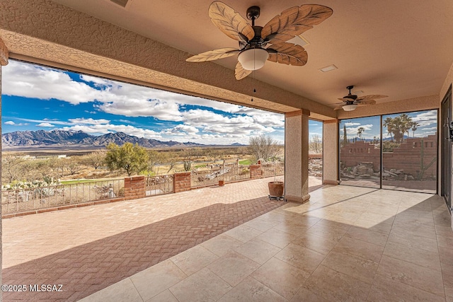 view of patio with a mountain view, fence, and ceiling fan