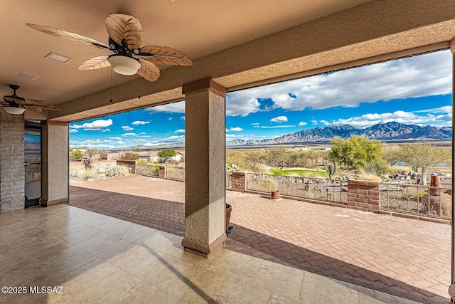 view of patio with a ceiling fan, a mountain view, and fence