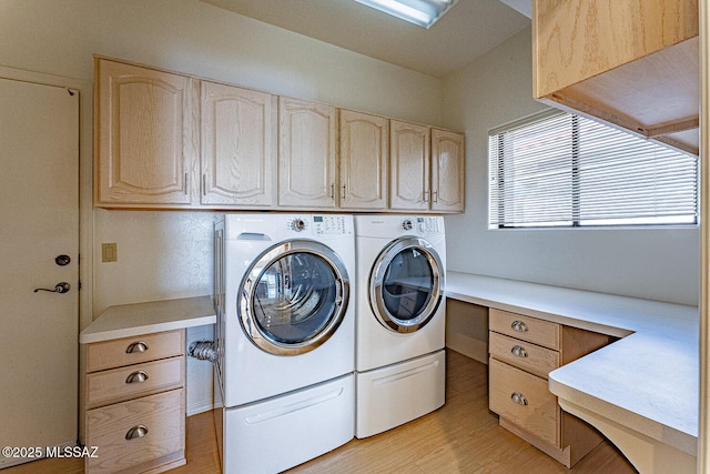 laundry area with light wood-type flooring, cabinet space, and washer and clothes dryer