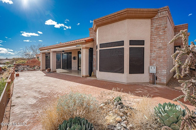 rear view of property featuring a patio area, a ceiling fan, and stucco siding