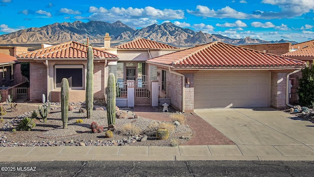 view of front of property with brick siding, a mountain view, concrete driveway, and a tiled roof