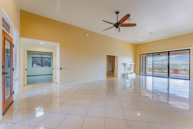 spare room featuring a healthy amount of sunlight, light tile patterned floors, a towering ceiling, and a mountain view