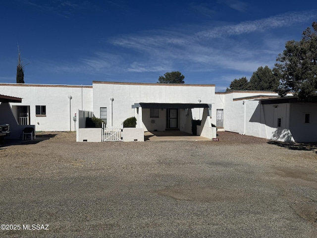 back of house featuring a gate, fence, and stucco siding