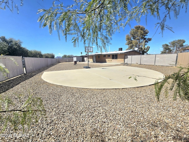 view of yard featuring a fenced backyard and basketball court