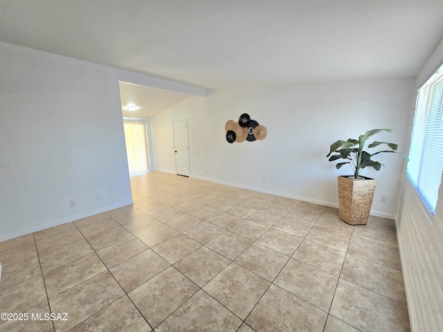 empty room with lofted ceiling, baseboards, and light tile patterned floors