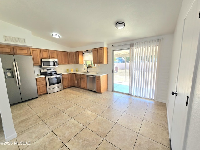 kitchen with stainless steel appliances, brown cabinetry, a sink, and light countertops