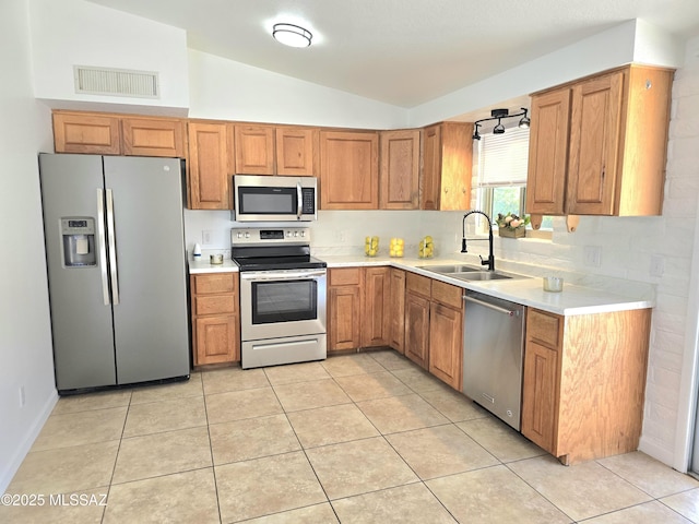 kitchen featuring brown cabinets, visible vents, stainless steel appliances, and a sink