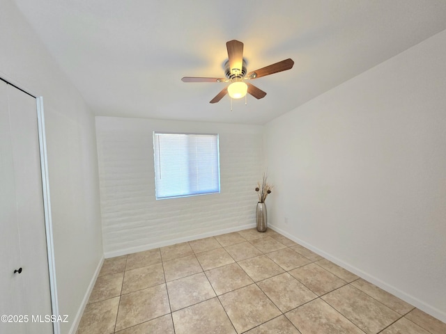 spare room featuring light tile patterned floors, a ceiling fan, and baseboards