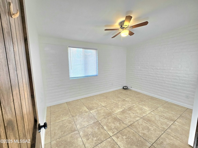 empty room with light tile patterned floors, brick wall, and ceiling fan