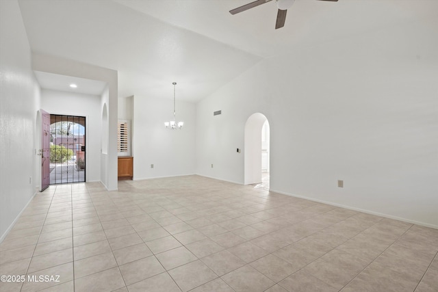 empty room with high vaulted ceiling, light tile patterned floors, arched walkways, and ceiling fan with notable chandelier