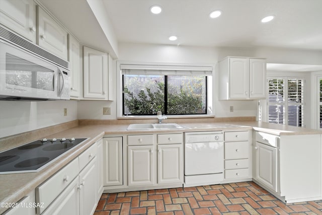 kitchen with recessed lighting, white appliances, a sink, white cabinetry, and light countertops