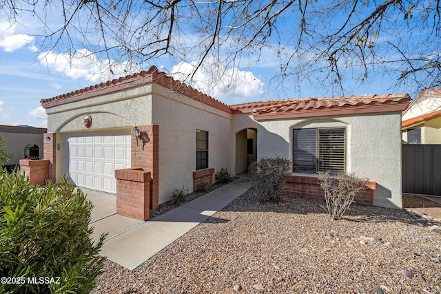 mediterranean / spanish home with an attached garage, a tiled roof, and stucco siding