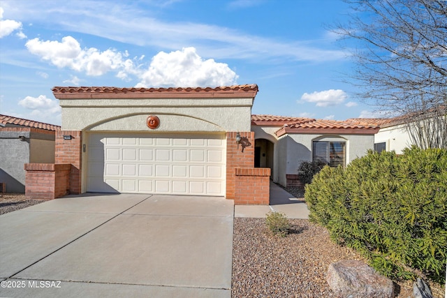 mediterranean / spanish home with concrete driveway, brick siding, an attached garage, and stucco siding