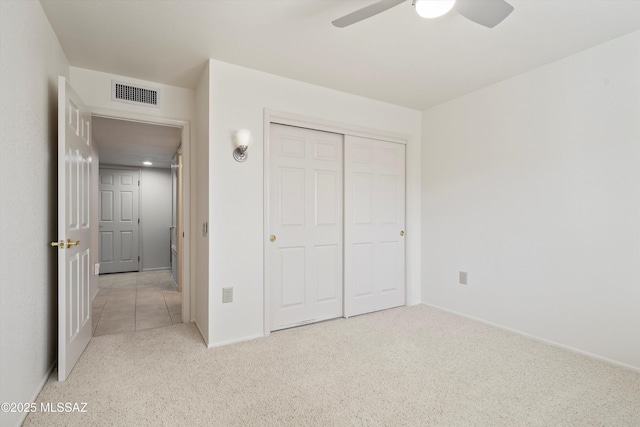 unfurnished bedroom featuring light colored carpet, a closet, visible vents, and ceiling fan