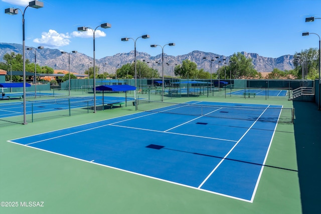 view of sport court with a mountain view and fence