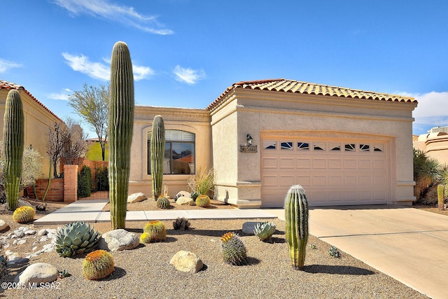 mediterranean / spanish-style home featuring a garage, concrete driveway, a tile roof, and stucco siding