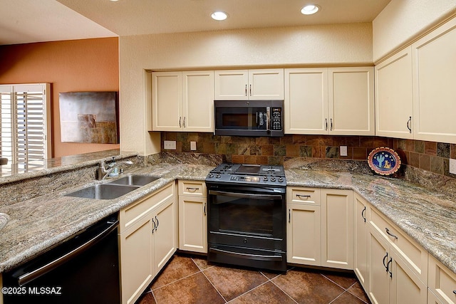 kitchen featuring a sink, light stone countertops, cream cabinets, black appliances, and backsplash