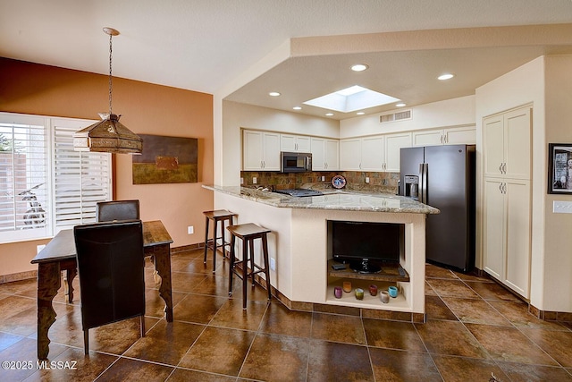 kitchen featuring light stone counters, stainless steel appliances, visible vents, white cabinetry, and hanging light fixtures