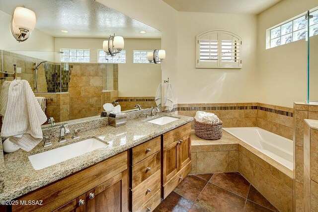 full bath with double vanity, walk in shower, a sink, and a bath