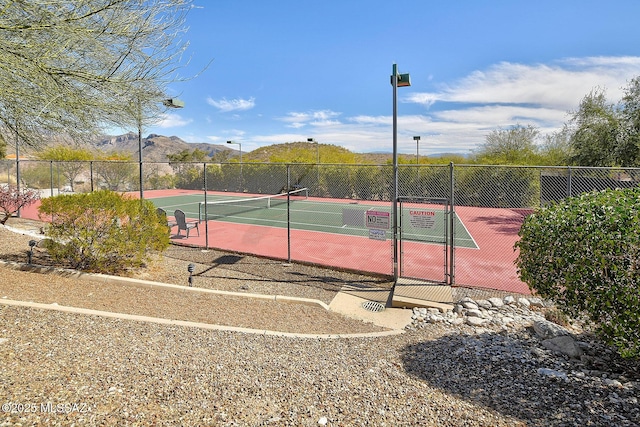 view of tennis court featuring fence and a mountain view