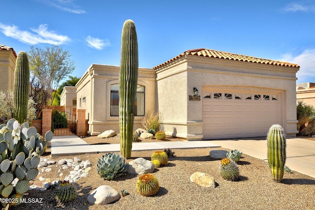 mediterranean / spanish house with stucco siding, concrete driveway, fence, a garage, and a tiled roof