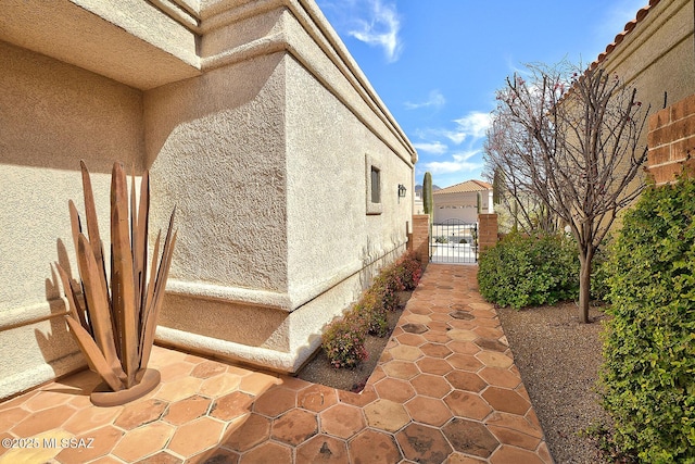 view of property exterior with fence, a gate, and stucco siding