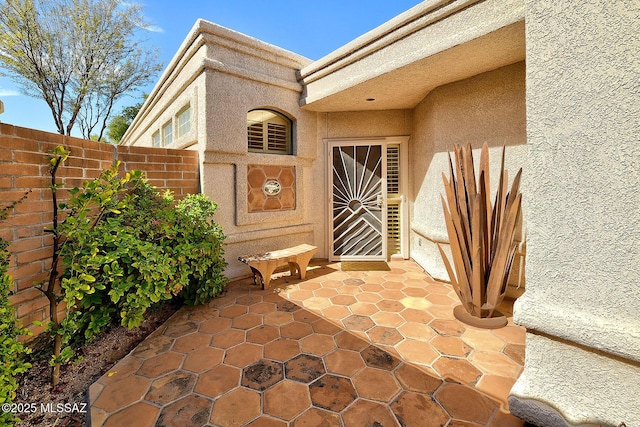 doorway to property featuring a patio, fence, and stucco siding