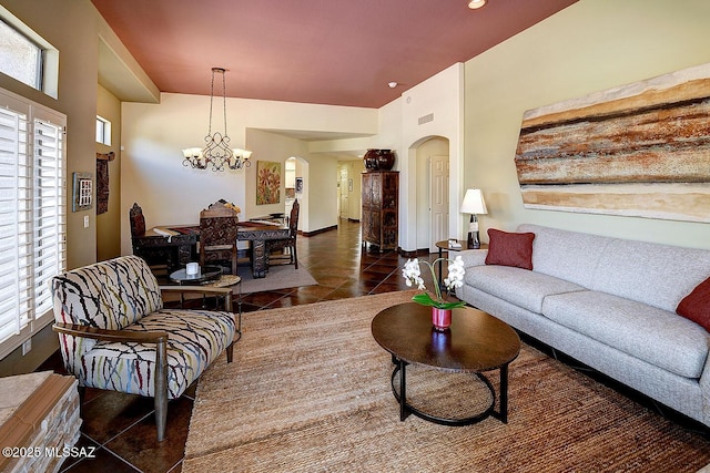 living room with a healthy amount of sunlight, arched walkways, a chandelier, and dark tile patterned flooring