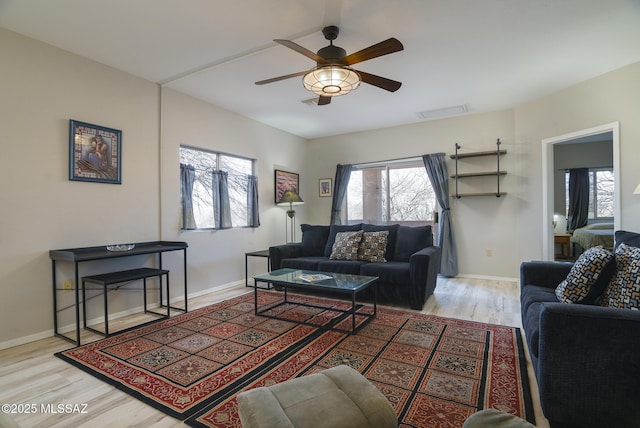 living room featuring baseboards, wood finished floors, visible vents, and a ceiling fan