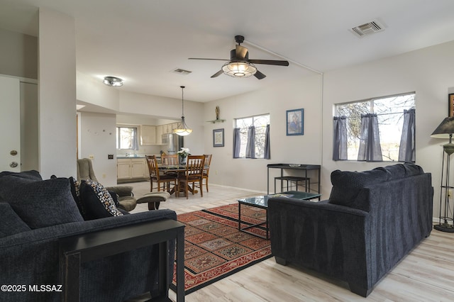 living area featuring light wood-type flooring, visible vents, and ceiling fan