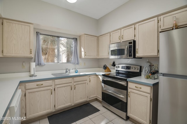 kitchen with light tile patterned floors, light brown cabinets, stainless steel appliances, a sink, and light countertops