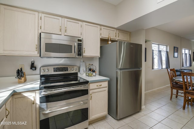 kitchen with light tile patterned floors, baseboards, appliances with stainless steel finishes, and light countertops